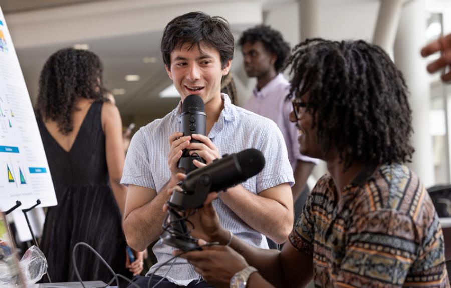 Students smiling and using podcast microphones